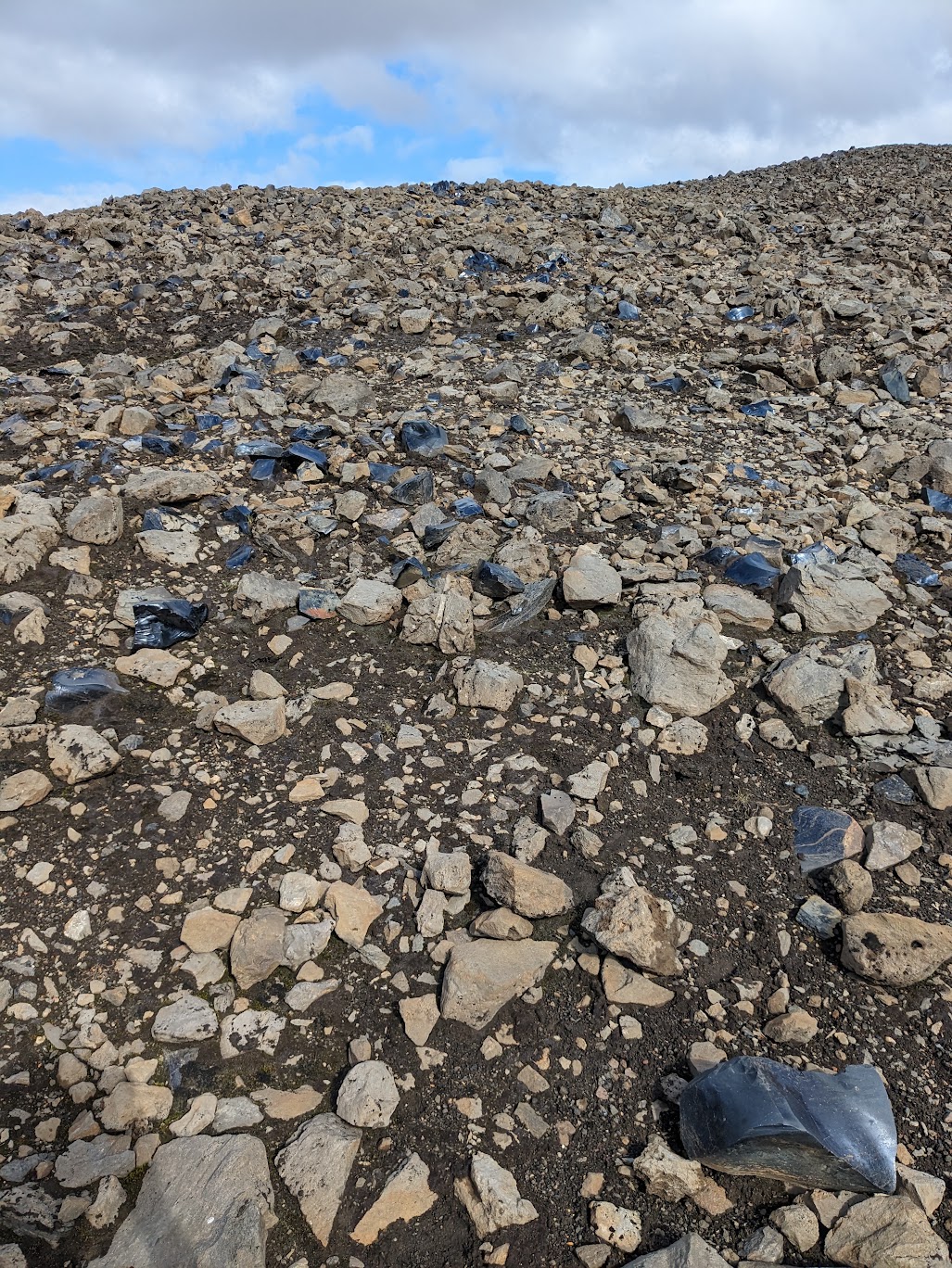 A picture of the ground at Hrafntinnusker, which means obsidian reef in Icelandic. The ground is littered with big chunks of obsidian rock.