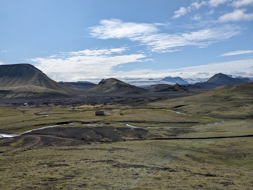 A picture of the change in landscape from the previous days. There are more grasses and mosses as well as some huts and minor structures among the lavafield.