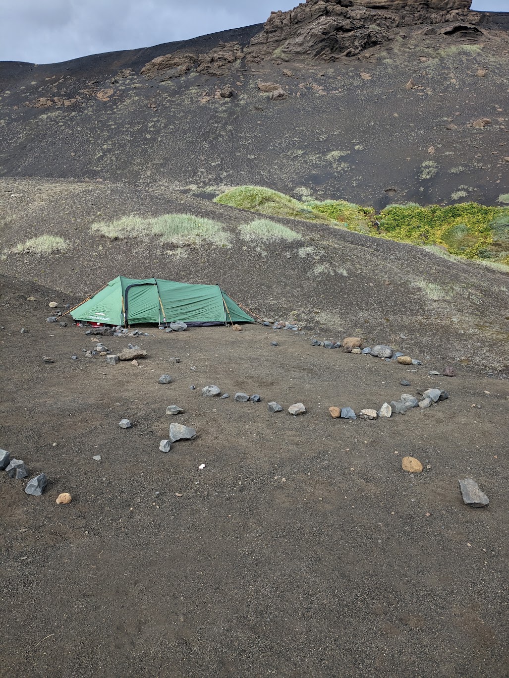A pitched tent with a few stones marking the area around it.